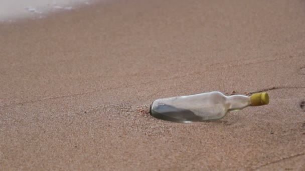 समुद्र तरंगों के साथ रेत समुद्र तट पर खाली बोतल — स्टॉक वीडियो