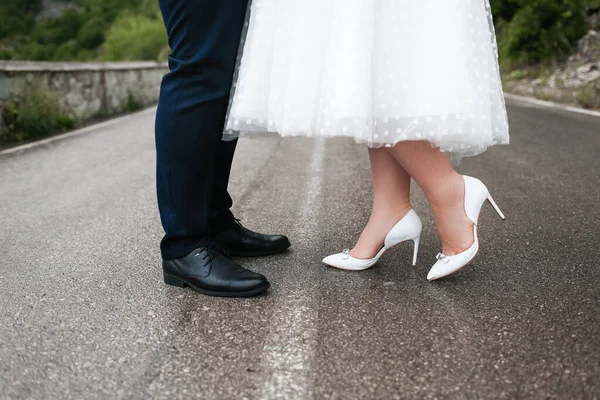 A noiva caminha em um vestido de noiva na estrada para as montanhas. — Fotografia de Stock