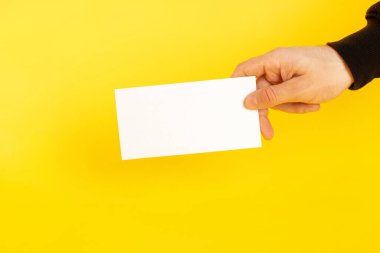 Kartvizitli eller. Renkli sarı arka planda beyaz bir kart tutuyor..