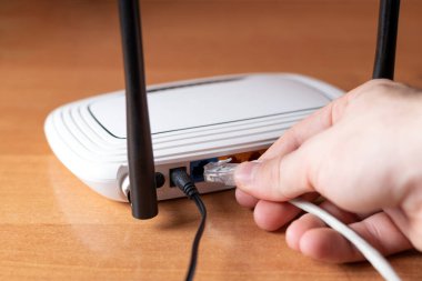 Adam internet kablosunu yönlendiriciye takıyor.