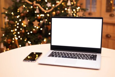 Beyaz ekran dizüstü bilgisayarın önü. Evde Noel ağacı ışığı var. Uzaktan kumanda. Serbest çalışıyorum. Evden çalışıyorum. Telework.