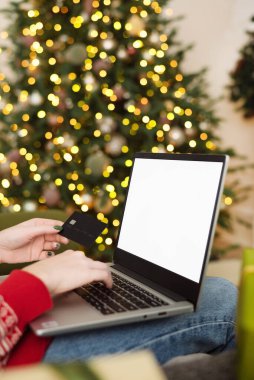Noel alışverişi, satış ve indirimler kış tatilleri boyunca promosyonlar, evde online alışveriş. Model-up. Dizüstü bilgisayarda kadın eli ve kredi kartı ve bulanık ışık..
