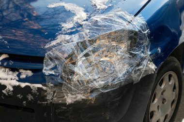 Arabanın kırık farları şeffaf bantla kapatılmış. yakın plan.
