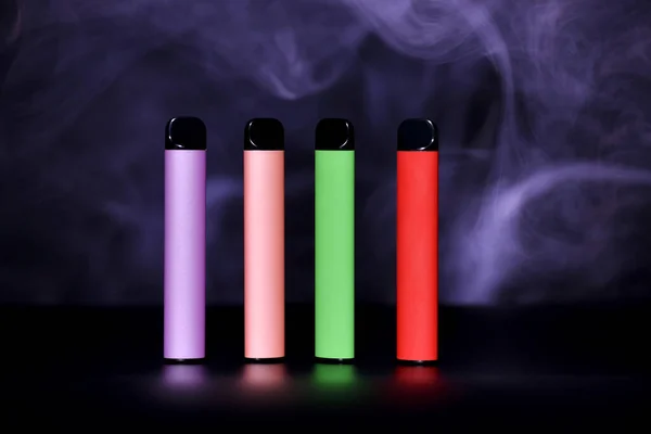 一套五颜六色的一次性电子香烟 背景为黑色 烟色浓郁 现代吸烟 蒸气和尼古丁的概念 — 图库照片