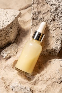 Damlatan bir şişe nemlendirici, taşların üzerinde yüzler için serum kum, arka plan, yaz yüz bakımı..