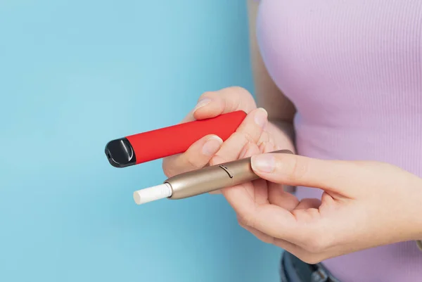 Disposable electronic cigarette and iqos in hand. an alternative way of consuming tobacco. modern smoking, choice.