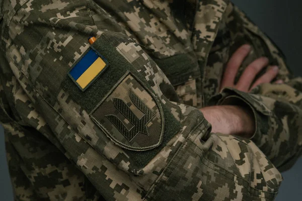 Ukrainian soldier wearing military uniform with flag and chevron depicting trident - Ukrainian emblem and national symbol