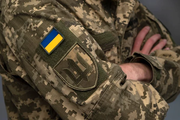 Ukrainian soldier wearing military uniform with flag and chevron depicting trident - Ukrainian emblem and national symbol