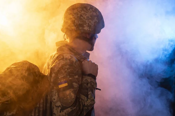 Armed Forces of Ukraine. A close-up photo of a military man in the shape of a pixel with military  backpack in colored smoke. Defender of Ukraine