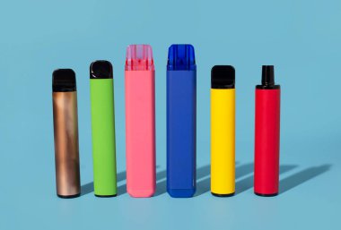 Mavi arka planda tek kullanımlık renkli elektronik sigaralar. Modern sigara konsepti