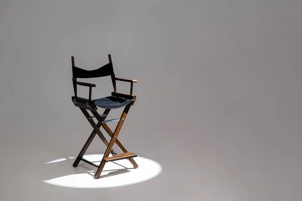 Directors chair stands in the beam of light. Space for text. Vacant chair. The concept of selection and casting.