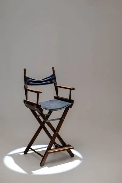 Directors chair stands in the beam of light. Space for text. Vacant chair. The concept of selection and casting.