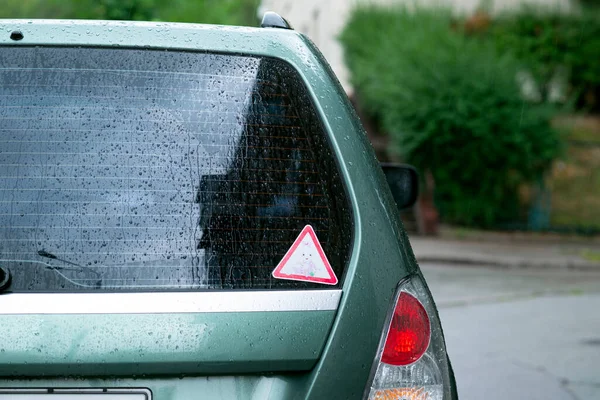 Back window of a green car parked on the street in rainy day, rear view. Mock-up for sticker or decals. High quality photo