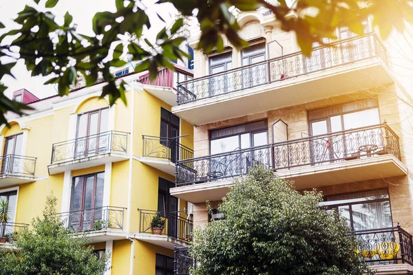 The facade of house with beautiful balcony in summer sun rays. Balcony with metal railings. Laconic minimalist concept.