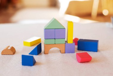 Ev masasında renkli tahta bloklar var. Yaratıcılık oyuncakları. Çocukların yapı taşları. Geometrik şekiller - daire, üçgen, kare, dikdörtgen. Mantıklı düşünme kavramı