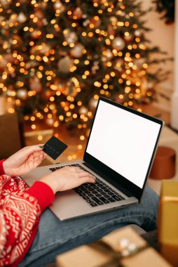 Noel alışverişi, satış ve indirimler kış tatilleri boyunca promosyonlar, evde online alışveriş. Model-up. Dizüstü bilgisayarda kadın eli ve kredi kartı ve bulanık ışık..
