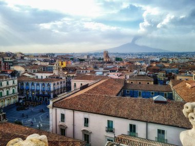 Sicilya 'nın tarihi şehir merkezinde balkonları ve sokak restoranları olan eski binaların havadan görünüşü. Arka planda Etna volkanı var..