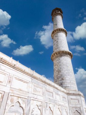 Agra, Uttar Pradesh, Hindistan 'da bulunan Tac Mahal' i çerçeveleyen dört minareden birinin mavi gökyüzü arkaplanına doğru bakın.