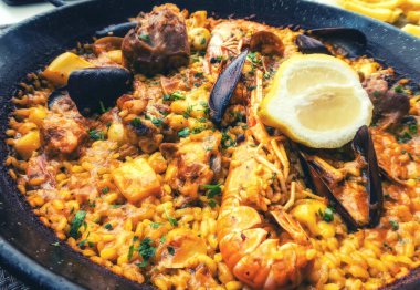 Klasik İspanya yemeği, geleneksel tavada deniz ürünleri paella, karidesli İspanyol paella, kıskaç, midye, bezelye ve yukarıdan taze limon dilimleri.