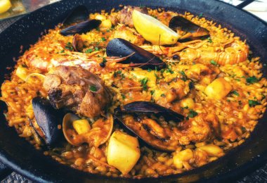 Klasik İspanya yemeği, geleneksel tavada deniz ürünleri paella, karidesli İspanyol paella, kıskaç, midye, bezelye ve yukarıdan taze limon dilimleri.
