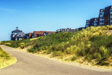 Yat limanının arkasındaki kumulların tepesinde siyah çatılı güzel beyaz bir otel.