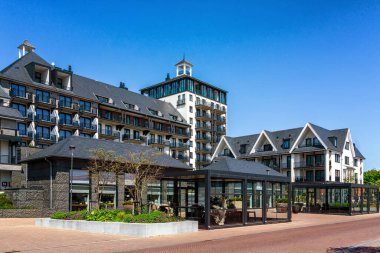 Yat limanının arkasındaki kumulların tepesinde siyah çatılı güzel beyaz bir otel.