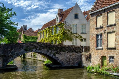Bruges Belçika 'nın klasik taş evleri ve kanal üzerine köprü. Antik ortaçağ sokak manzarası. Yazın güneşli bir günde mavi gökyüzü bulutları..