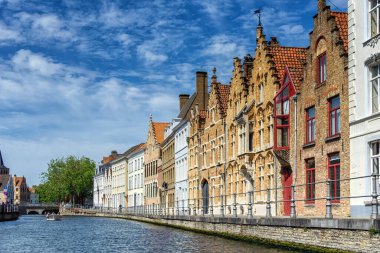 Ortaçağ evleriyle manzaralı şehir, Brugge 'de turistlerle dolu tekne ve kanal