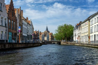 Ortaçağ evleriyle manzaralı şehir, Brugge 'de turistlerle dolu tekne ve kanal