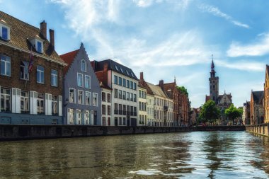Kanaldaki tekneden Jan Van Eyck Meydanı 'nın görüntüsü. Mavi gökyüzü ve biraz bulut. Merkezdeki fakir yamaç yüksek bir kule ve Bruges 'ün tipik mimarisidir..