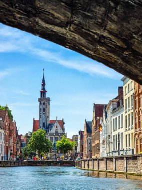 Kanaldaki tekneden Jan Van Eyck Meydanı 'nın görüntüsü. Mavi gökyüzü ve biraz bulut. Merkezdeki fakir yamaç yüksek bir kule ve Bruges 'ün tipik mimarisidir..