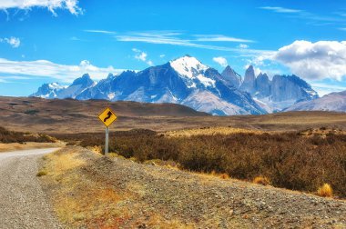 Torres del Paine Ulusal Parkı 'ndaki çakıl yolu. Dağlar ve kayalar kar ve buzla kaplıdır.