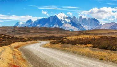 Torres del Paine Ulusal Parkı 'ndaki çakıl yolu. Dağlar ve kayalar kar ve buzla kaplıdır.