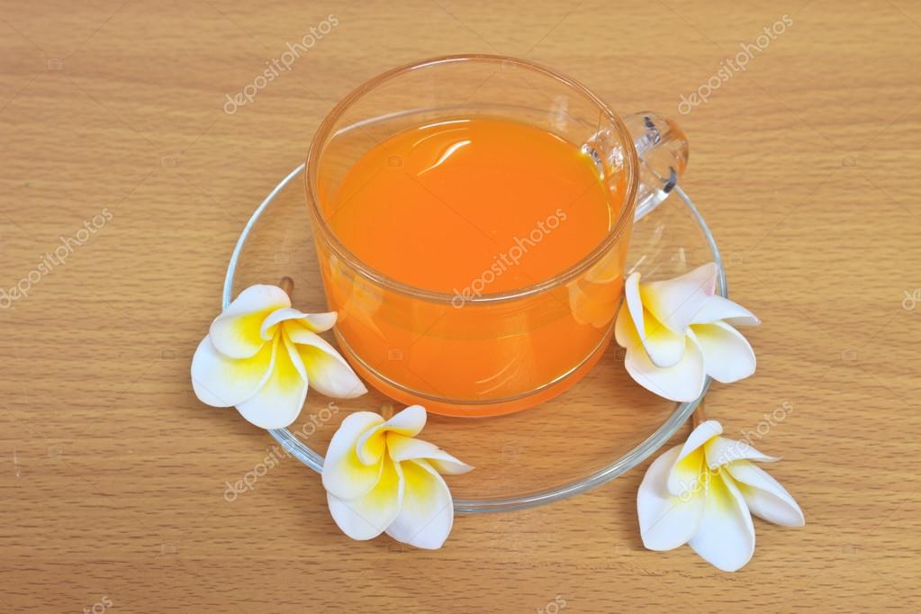 Orange juice with flowers on wooden table — Stock Photo © sirichai2514
