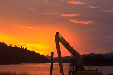 Şantiye yakın göl günbatımı üzerinde makine