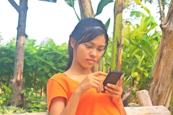Νεαρό κορίτσι που κάθεται με την ξύλινη κούνια με το κινητό τηλέφωνο — Φωτογραφία Αρχείου