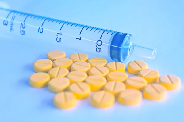Medicamento en tabletas y jeringa de insulina en tono azul borroso — Foto de Stock