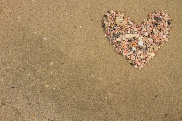 Cuore fatto di conchiglie che giacciono su una spiaggia di sabbia — Foto Stock