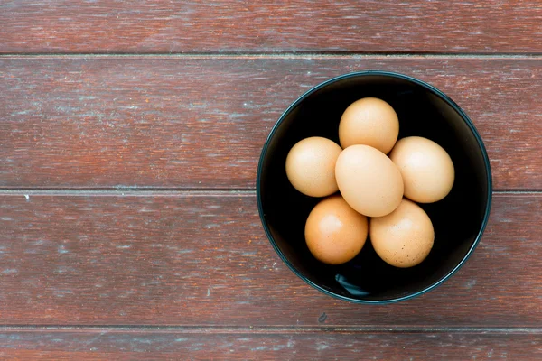 Huevos en tazón sobre fondo de madera — Foto de Stock