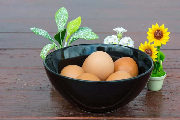 Huevos en tazón con las pequeñas flores sobre fondo de madera — Foto de Stock