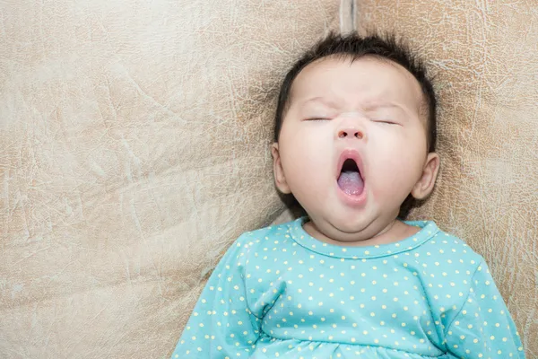 Portrait of a yawning baby girl on a leather background — Stock Photo, Image