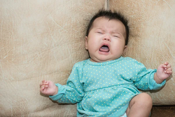 皮革背景上的哭泣婴儿女孩的画像 免版税图库图片
