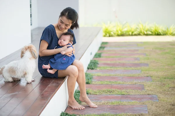 Mom and Baby are watching a puppy on wooden balcony — Stock Photo, Image