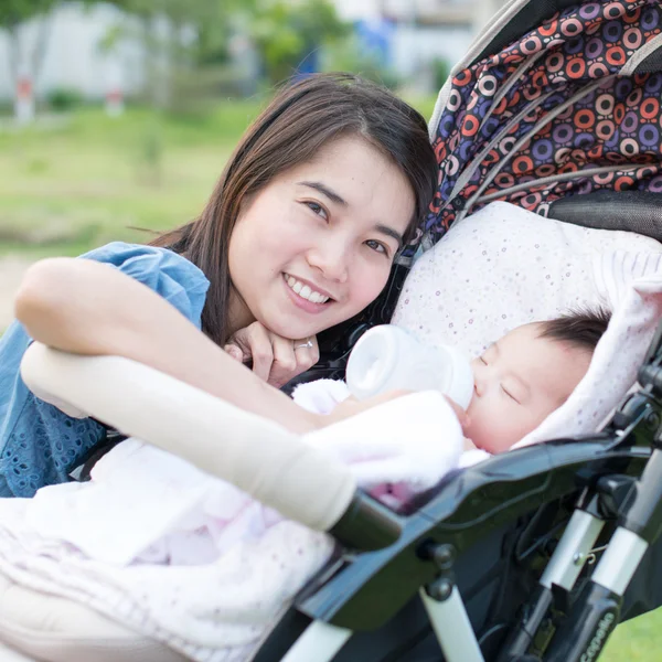 Happy asian mother feeding to baby on the stroller — Stock Photo, Image