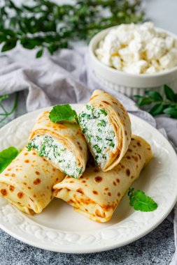 Pancakes stuffed with cottage cheese, parsley and dill in the form of rolls