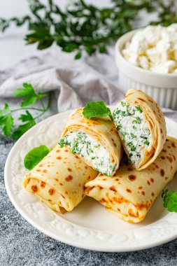 Pancakes stuffed with cottage cheese, parsley and dill in the form of rolls