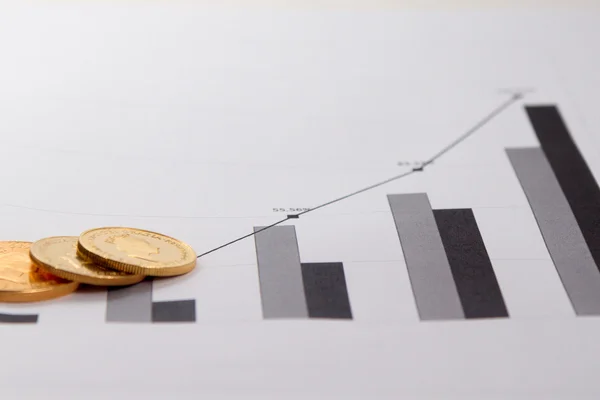 Gold coins on financial charts — Stock Photo, Image