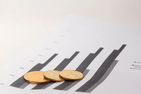 Gold coins on financial charts — Stock Photo, Image