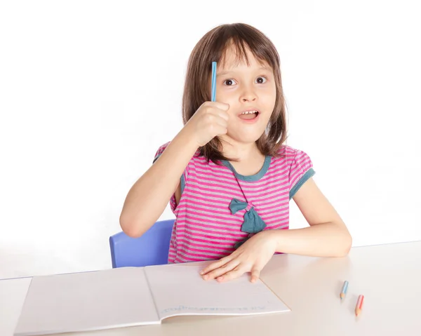 Child writing at desk gets an idea — Stock Photo, Image