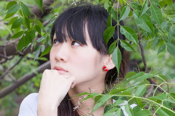 Asian girl standing amongst leaves — Stock Photo, Image